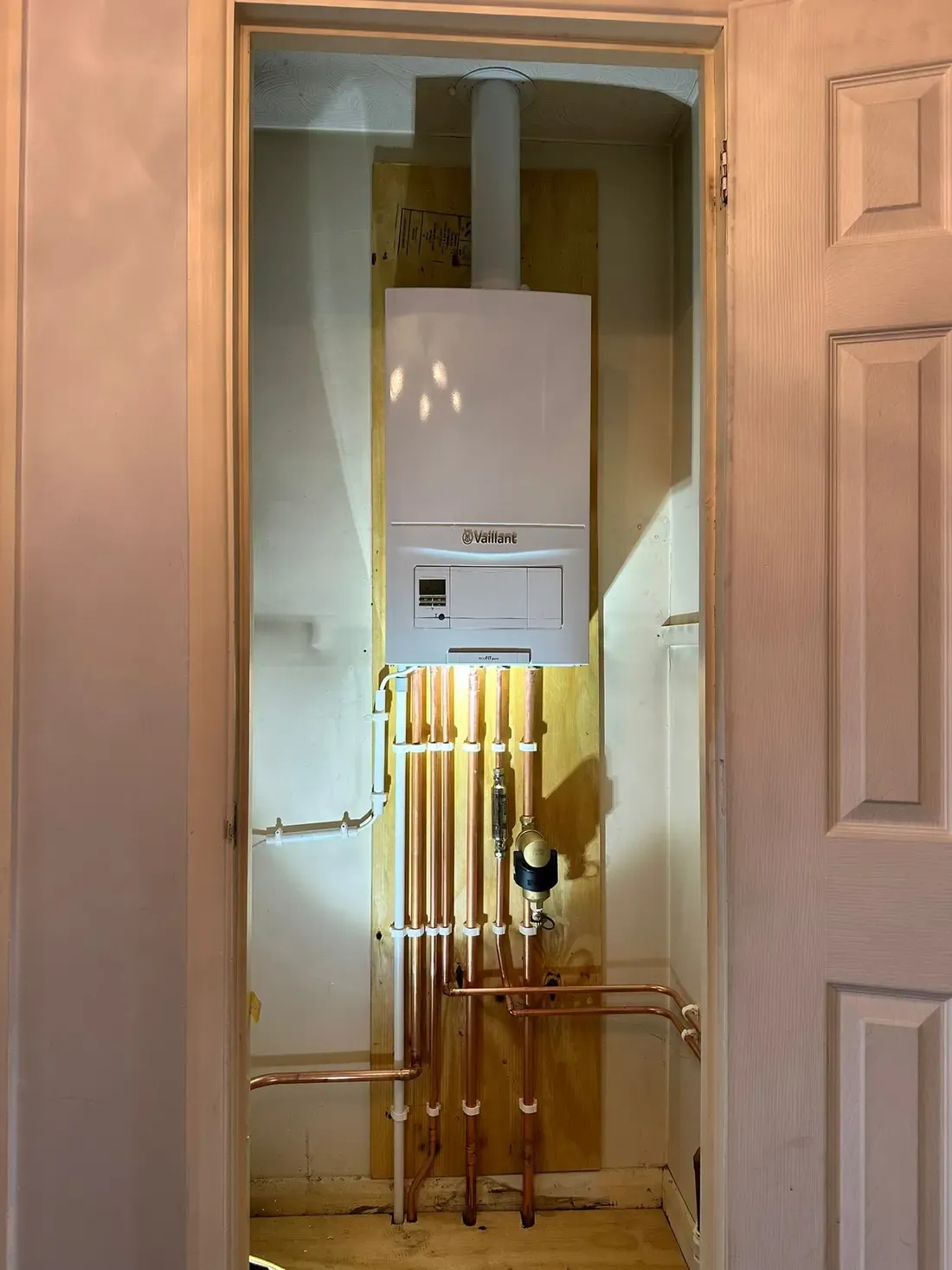 Vaillant boiler installed in a hallway cupboard with copper pipework